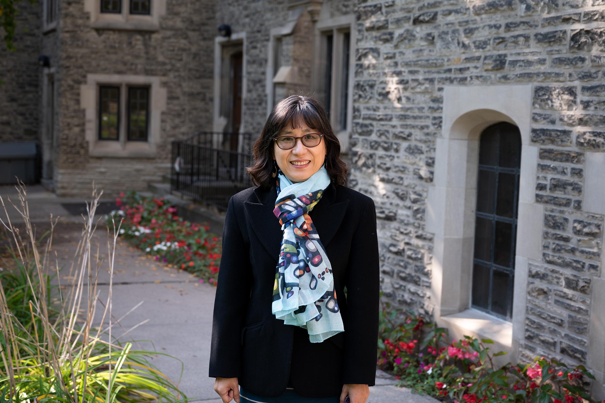 Principal HyeRan smiles outside of Emmanuel College on a fall day.