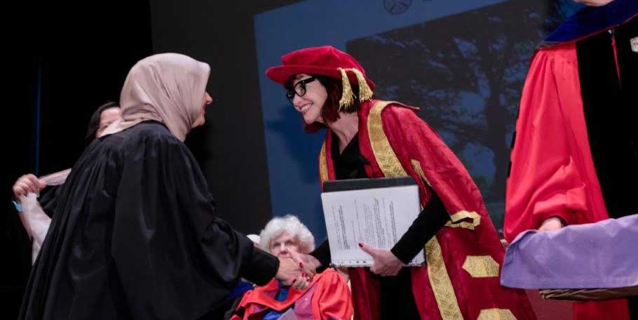Wendy Cecil shaking hands with a grad button